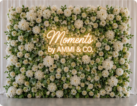 Green and white flower wall with Moments by AMMI & Company LLC logo
