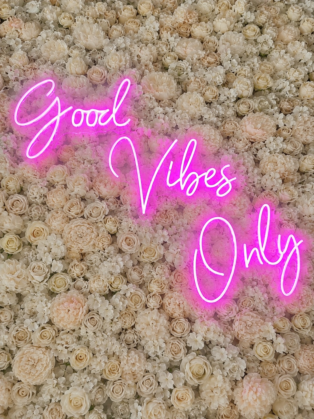 Good Vibes Only pink neon sign on white flower wall