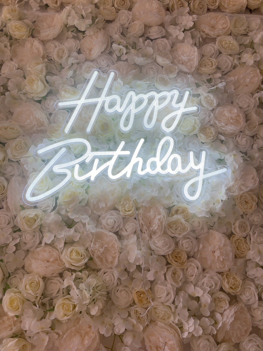 Happy Birthday neon sign on white flower wall